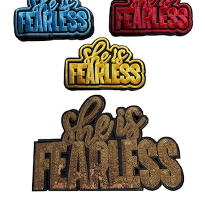 May include: Four embroidered patches with the phrase "She is Fearless". The patches are in blue, red, yellow, and gold. The gold patch is covered in sequins. The patches are on a white background.
