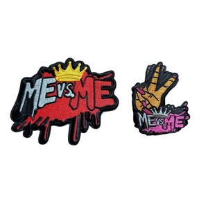 May include: Two embroidered patches. The larger patch features the text "ME vs ME" in black and white, with a red dripping effect and a gold crown. The smaller patch has the same text with a hand gesture.