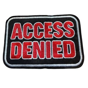 May include: A rectangular embroidered patch with a black background and a white border. The text ACCESS DENIED is stitched in bold red capital letters with a white outline, centered on the patch. The design features a clean, block-style font.