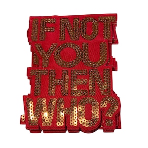 Peut inclure: Plusieurs écussons en tissu rouge avec le texte doré à paillettes « IF NOT YOU THEN WHO ? ». Les écussons sont rectangulaires avec des coins arrondis et empilés.