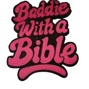 May include: Embroidered patch with the text "Baddie With a Bible" in pink script lettering on a black background. The patch has a layered design and a decorative border.