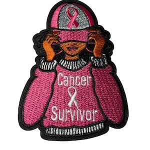 May include: Embroidered patch featuring a person wearing a pink sweater and hat, with a pink ribbon and the words "Cancer Survivor." The person has dark hair and orange skin. The patch has a black border and white accents.