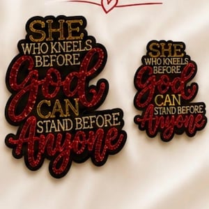 Pode incluir: Dois patches decorativos com o texto "FAITH OVER EVERYTHING". Os patches dizem "SHE WHO KNEELS BEFORE GOD CAN STAND BEFORE ANYONE" em letras vermelhas e douradas. A parte inferior da imagem diz "LARGE & SMALL SIZES".