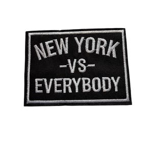 Può includere: Toppa rettangolare nera con testo ricamato bianco. Il testo recita "NEW YORK -VS- EVERYBODY" in un carattere sans-serif in grassetto. La toppa ha un bordo bianco e lo sfondo è nero.