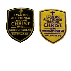 May include: Two embroidered patches with a shield shape. One is black with gold text and a gold cross, the other is yellow with purple text and a purple cross. The text reads "I CAN DO ALL THINGS THROUGH CHRIST WHO STRENGTHENS ME" and "PHILIPPIANS 4:13".