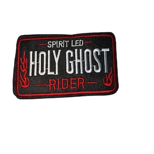 May include: A rectangular black embroidered patch with red trim. The patch features the words "SPIRIT LED" above "HOLY GHOST RIDER" in white, with red flame designs on the sides. The patch is likely for a jacket or vest.