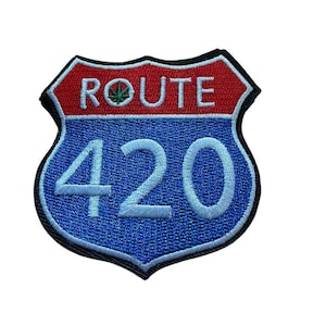 Puede incluir: Un parche bordado en forma de escudo con un borde negro. La sección superior es roja con el texto blanco ROUTE y un pequeño icono de hoja verde que reemplaza la letra O. La sección inferior es azul con el número 420 grande en blanco.