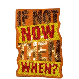 Peut inclure: Écusson en tissu orange avec l'inscription « IF NOT NOW THEN WHEN? » en paillettes dorées et rouges. Le patch a une bordure de paillettes jaunes et un bord ondulé.