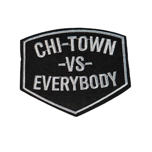 Op de afbeelding: Zwarte patch met witte tekst "CHI-TOWN -VS- EVERYBODY" in schildvorm. De patch heeft een witte rand en is waarschijnlijk een geborduurde of opstrijkbare patch.