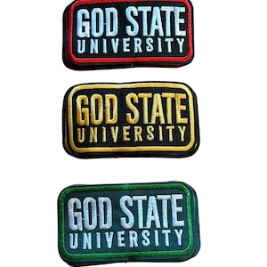 Puede incluir: Tres parches rectangulares bordados con el texto GOD STATE UNIVERSITY. El parche superior tiene texto blanco con borde rojo, el central tiene texto dorado con borde dorado y el inferior tiene texto blanco con borde verde sobre tela negra.