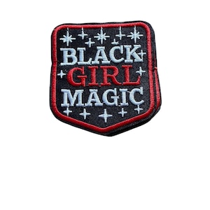 May include: Embroidered patch with the words "BLACK + GIRL + MAGIC" in white and red lettering. The patch has a black background with a red border and white star and cross accents.