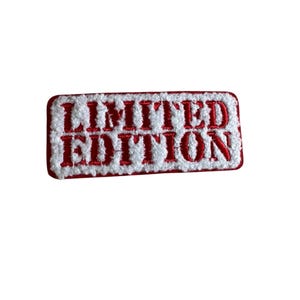 May include: A rectangular patch with the words "LIMITED EDITION" embroidered in red, outlined in white, and set against a white background. The patch has a fuzzy, textured appearance.