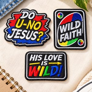 Puede incluir: Tres parches bordados con bordes negros. Un parche tiene forma de nube con texto en rojo, amarillo y azul que dice DO U-NO JESUS?. Un parche rectangular presenta un óvalo multicolor y el texto WILD FAITH. Un tercer parche rectangular dice HIS LOVE IS WILD!.