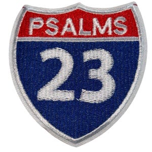 May include: Embroidered patch with a shield design. The top section is red with the word "PSALMS" in white. The bottom section is blue with the number "23" in white. The patch has a silver border.