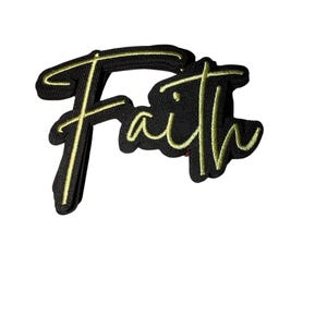 Puede incluir: Un parche bordado negro con la palabra "Faith" en cursiva. La palabra está delineada en color dorado, creando un efecto de contraste sobre el fondo negro. El parche está diseñado para ser cosido o planchado sobre tela.