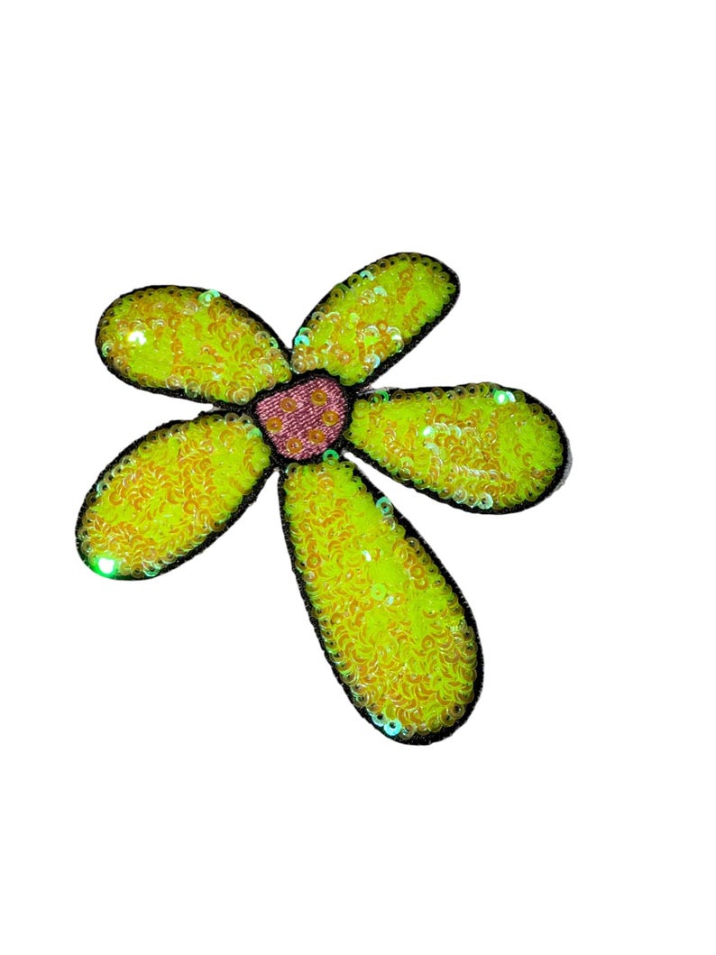 Puede incluir: Una flor decorativa con cinco p&eacute;talos, cada uno de un amarillo verdoso vibrante, delineados en negro. Los p&eacute;talos est&aacute;n cubiertos de lentejuelas, y el centro es rosa texturizado. La flor est&aacute; sobre un fondo blanco.