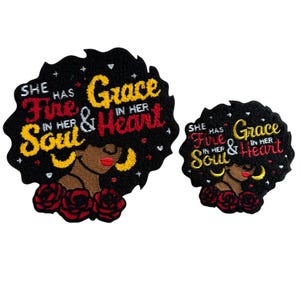 Peut inclure: Deux écussons noirs représentant une femme aux cheveux afro, aux lèvres rouges et aux boucles d'oreilles jaunes. Les écussons portent l'inscription "She has fire in her soul & grace in her heart" en rouge et jaune.