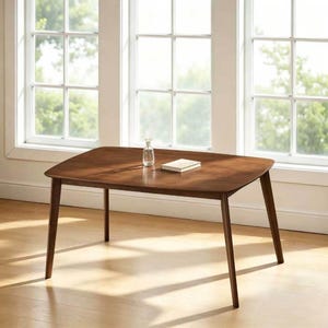 May include: A rectangular wooden dining table with a smooth, medium-brown finish and four tapered legs. The table features rounded corners and a flat surface. A small, clear glass vase and a closed, rectangular book are placed on the tabletop.
