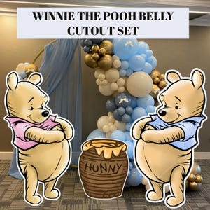 May include: Winnie the Pooh belly cutout set. The set includes two cartoon cutouts of Winnie the Pooh, a honey pot cutout, and a balloon arch in gold, white, and blue. The text "Winnie the Pooh Belly Cutout Set" is at the top.