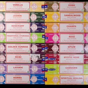 Può includere: Una collezione di scatole di incenso Satya, ognuna con un profumo diverso come Vaniglia, Gelsomino e Rosa. Le scatole sono colorate, con testo bianco e rosso e un logo circolare. Ogni scatola contiene 15g di incenso.