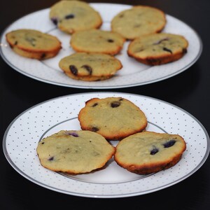 May include: Two white plates with a variety of light brown muffins with blueberries. The muffins are arranged in a circular pattern on the plates.