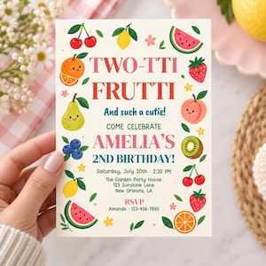 May include: A rectangular invitation card with a cream background featuring colorful illustrations of cherries, oranges, pears, blueberries, lemons, watermelons, strawberries, peaches, and kiwis. The text reads TWO-TTI FRUTTI, And such a cutie!, COME CELEBRATE AMELIA'S 2ND BIRTHDAY!, Saturday, July 20th, 2:30 PM, The Garden Party House, 123 Sunshine Lane, New Orleans, LA, RSVP, Amanda, 123-456-7890.