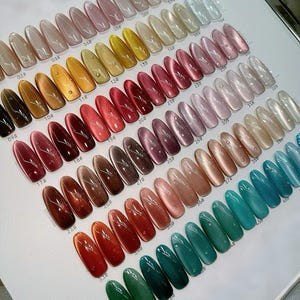 May include: A color swatch display board featuring numerous oval-shaped artificial nail tips arranged in rows. Each nail tip displays a cat-eye magnetic polish finish with a shimmering diagonal line, labeled with numerical identifiers from 02 to 41.