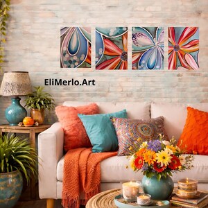 May include: Four abstract floral paintings in blue, pink, and orange hues hang above a white sofa with colorful pillows and an orange throw. A turquoise vase holds a bouquet of flowers. The text "EliMerlo.Art" is visible.