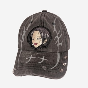 Könnte beinhalten: Verwaschene schwarze Baseballkappe mit aufgesticktem Manga-Charakter-Patch mit Zigarette. Silberne Tribal-Designs und japanischer Text. Silberne Nieten am Schirm.