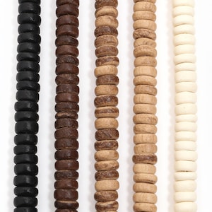 May include: Five vertical strands of round, flat-edged wooden beads arranged in a gradient from black to dark brown, medium brown, light tan, and off-white. Each strand consists of uniform, circular beads strung together in a straight line.