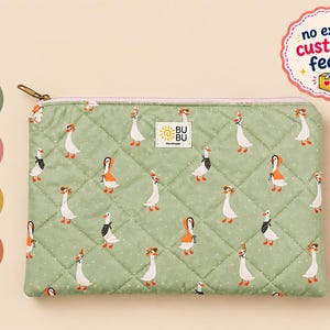 Peut inclure: Une pochette zippée matelassée vert sauge avec un motif répétitif d'oies blanches portant des accessoires orange et noirs. Une étiquette rectangulaire blanche avec le texte BU BU Handmade est centrée sur le devant. Options de tailles 13, 14, 15 et 16 pouces.