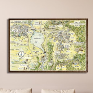 May include: A rectangular wall art print titled Map of Beatrix Potter's World, featuring a detailed illustrated landscape map in muted green, yellow, and brown tones, enclosed within a dark brown walnut frame and displayed on a plain wall.