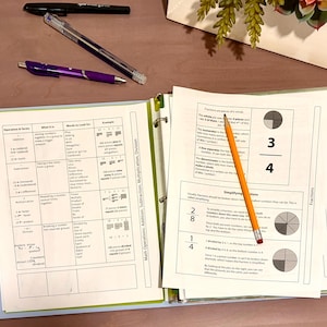 May include: A light blue three-ring binder containing educational math worksheets on operations and fractions. A yellow pencil rests on the pages, while a black pen and a purple pen are placed nearby on the surface above the open binder.