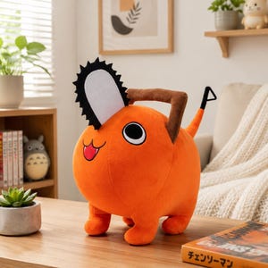 May include: An orange plush toy shaped like a cartoon character with a chainsaw head and a tail. The toy has a black and white chainsaw blade, brown handles, and a smiling face with a red tongue. The toy is on a wooden table.
