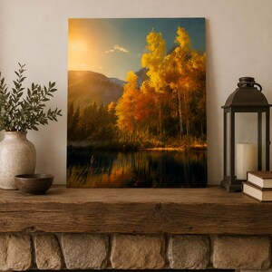 Puede incluir: Una impresión de arte mural rectangular que representa un paisaje con árboles de otoño de color amarillo dorado iluminados por un sol brillante, sobre un fondo de montañas oscuras y un lago tranquilo que refleja el follaje vibrante y la luz cálida.