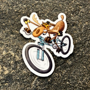 May include: A cartoon moose wearing a helmet and riding a blue bicycle with black tires. The moose is holding the handlebars with its front hooves and has a determined expression on its face.