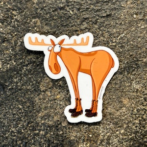 May include: A cartoon sticker of a brown moose with large eyes and a surprised expression. The moose is wearing brown boots and has a white background with the text "@Foxnook" in the bottom right corner.
