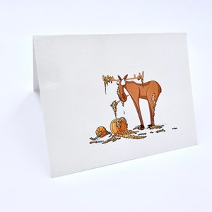 May include: A cartoon illustration of a moose covered in fall leaves, standing next to a pumpkin. The moose has a surprised expression on its face.