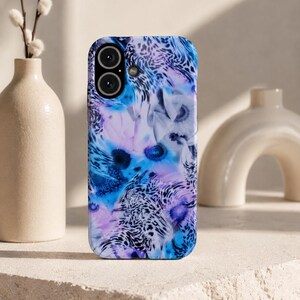 Könnte beinhalten: Eine rechteckige Smartphone-Hülle mit einem lebendigen, abstrakten Muster aus Blau- und Violetttönen, kombiniert mit einem schwarzen Leopardenmuster. Die Hülle verfügt über einen kreisförmigen Ausschnitt für eine Doppelkamera und eine kleine Blitzöffnung.