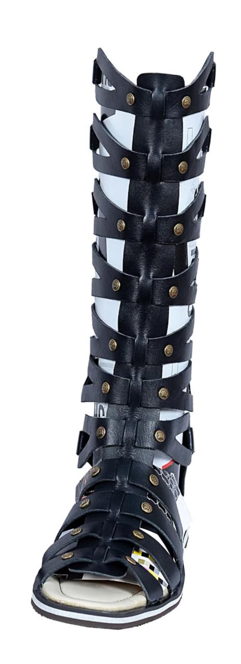 May include: Black leather gladiator sandals with multiple straps and gold-colored rivets. The sandals have an open toe design and a white sole. The tall design extends up the leg, offering a unique style.