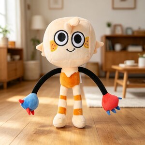 May include: A plush doll with a round, light peach-colored head, large black eyes, and a small smile. The doll has black arms, orange and white striped legs, and blue and red hands. The doll is wearing an orange outfit and has small orange and yellow accents on its face.