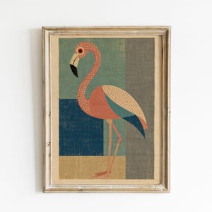 May include: A framed wall art print featuring a stylized flamingo with a pink, orange, and blue patterned body. The bird stands against a geometric background of muted green, dark blue, and tan rectangular blocks within a light wood frame.