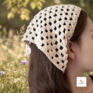 May include: A cream-colored crochet headscarf featuring a triangular shape with an openwork diamond pattern. The headscarf is tied at the back with two small crocheted ties. A small square logo with the text PASHMIQUE BY KOTA is visible.