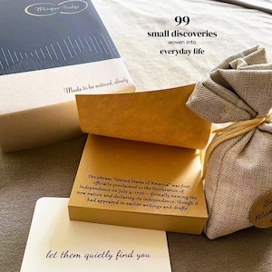 May include: A box labeled Whisper-Nudge, a stack of tan paper notes with text about the United States of America, a small beige fabric drawstring pouch, and a white card with the text let them quietly find you printed on the front.
