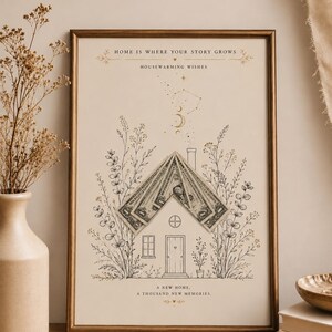 Könnte beinhalten: Ein gerahmter Druck mit einer Strichzeichnung eines Hauses, umgeben von Wildblumen. Das Dach besteht aus gefalteten Ein-Dollar-Scheinen. Der Text lautet: HOME IS WHERE YOUR STORY GROWS, HOUSEWARMING WISHES, A NEW HOME, A THOUSAND NEW MEMORIES.
