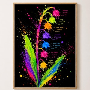 Könnte beinhalten: Ein gerahmter Kunstdruck auf schwarzem Hintergrund mit einer leuchtend neonfarbenen Maiglöckchenblume mit Farbspritzereffekten. Der Text enthält Phrasen wie bloom gently, stay hopeful, trust your timing und light returns.