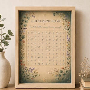 Könnte beinhalten: Gerahmter Druck mit einem Wortsuchrätsel. Der Text lautet "A LITTLE PUZZLE FOR YOU" und "Find the hidden message to reveal your gift." Das Rätsel ist von floralen und Blattillustrationen umgeben.