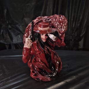 May include: A red and black figurine of a character with a red hat, coat, and a gun. The figure has long black hair and a sinister smile. The background is a dark, textured surface.