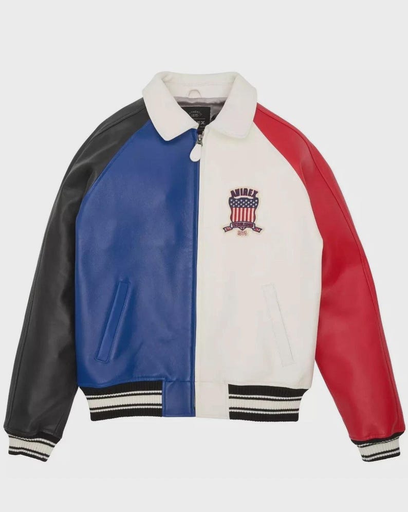 May include: A color-blocked leather jacket in black, blue, white, and red. The jacket features a white collar, a zipper closure, and a ribbed hem and cuffs with black and white stripes. An emblem with text is on the front.