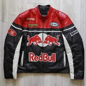 Könnte beinhalten: Eine Motorradjacke aus Leder in Schwarz, Rot und Weiß mit dem Red Bull Logo, zwei roten Stieren sowie den Schriftzügen Red Bull, Motul, Michelin, Helmet, TRG und Alpinestars. Die Jacke hat einen Stehkragen, einen Frontreißverschluss und weiße Akzente.